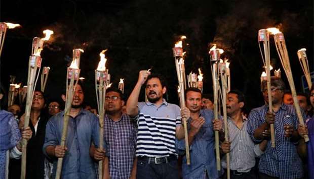 Demonstrators hold torches in a protest against the attack on prominent Bangladeshi writer Zafar Iqbal, in Dhaka on Saturday.