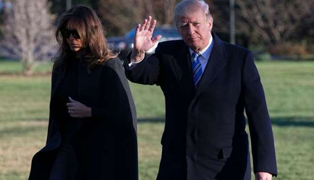 US President Donald Trump waves to reporters as he walks into the East Wing of the White House with First Lady Melania Trump after arriving at the White House on Marine One on March 3, 2018 in Washington, DC