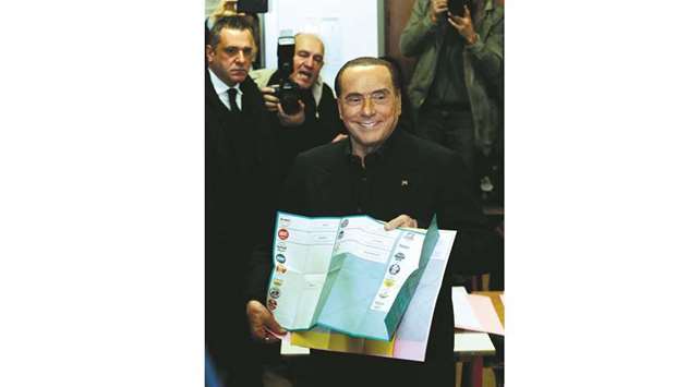 Berlusconi holds his ballot as he prepares to cast his vote at a  polling station in in Milan.