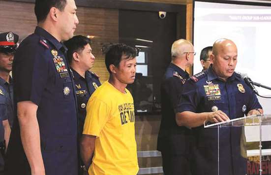 This handout photo taken and released yesterday shows Philippine National Police (PNP) chief Ronald Dela Rosa speaking next to Nasser Lomondot (yellow), a suspected pro-Islamic State militant, during a press conference at the PNP headquarters in Manila.