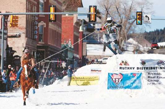 Rider Josh Abbott races down Harrison Avenue while skier Mike Fries airs out off the final jump of the Leadville ski joring course during the 70th annual Leadville Ski Joring weekend competition in Leadville, Colorado. Ski Joring, which has its origins as a competitive sport in Scandinavia, has been adapted over the years to include jumps, slalom gates, and spearing rings for points. Leadville has been hosting Ski Joring contests since 1949.