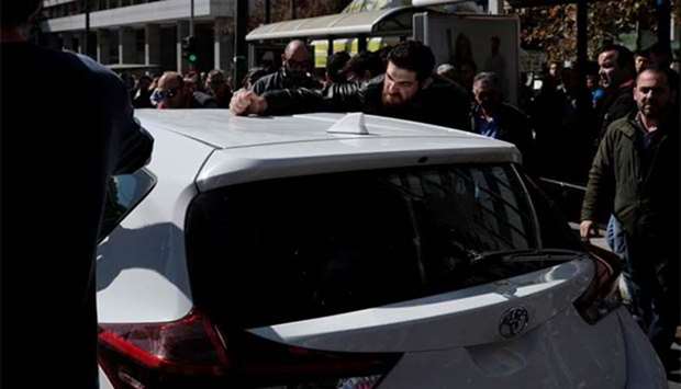 Greek taxi drivers attack a vehicle during a protest against taxi-hailing apps such as Uber in Athens on Tuesday.