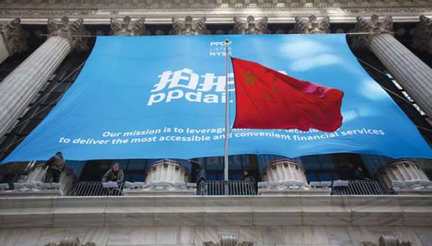 The Peopleu2019s Republic of China flag flies in front of PPDAI Group Inc signage displayed outside of the New York Stock Exchange. With the probe into China, known as a Section 301 action, US officials are considering a more targeted approach that would seek to rein in Chinese investments, sources say.
