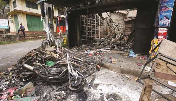A soldier stands guard near a burnt shop and a motorbike after a clash between two communities in Digana, central district of Kandy, yesterday.