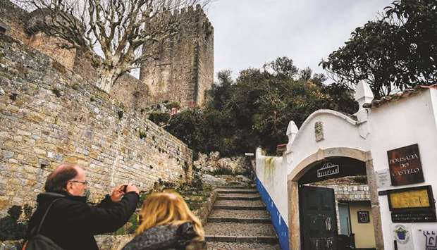 A tourist takes pictures at the entrance of the u2018Pousada do Castelou2019 (The Castleu2019s Inn) in the medieval town of Obidos in central Portugal.