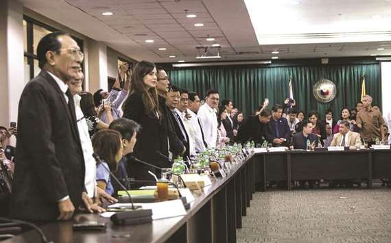 Members of the Philippine Congress stand to indicate their vote during a House of Representatives hearing in Manila.