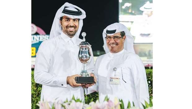 Raqeeu2019s representative Mansoor Shahwan al-Hajri (left) receives the traineru2019s trophy from Qatar Racing and Equestrian Club (QREC) deputy chief steward Abdulla Rashid al-Kubaisi after the four-year-old colt won the Rodat Al Maida Cup at the QREC on Wednesday. PICTURE: Juhaim