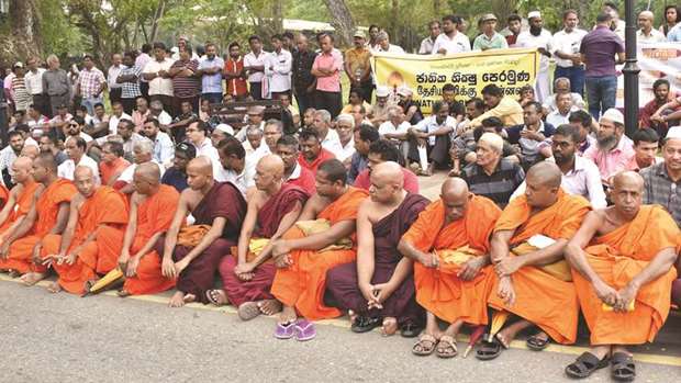 Members of the Peopleu2019s Liberation Front group and Buddhist monks sit at a roadside as they hold a rally calling for calm following deadly communal violence in other parts of Sri Lanka, in Colombo yesterday.