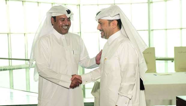 Ahmad al-Namla and Hamad Jumaa al-Mannai shake hands after signing the agreement.rnrn