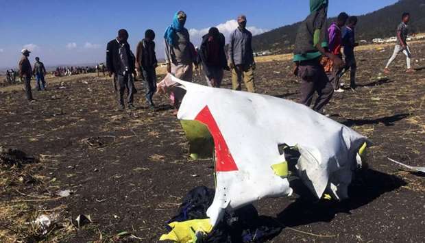 People walk past a part of the wreckage at the scene of the Ethiopian Airlines Flight ET 302 plane crash, near the town of Bishoftu, southeast of Addis Ababa, Ethiopia