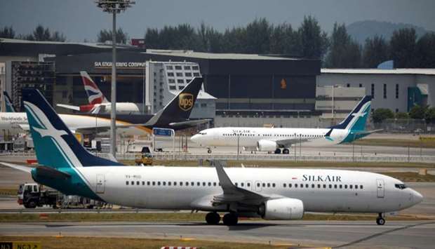 A SilkAir Boeing 737 Max 8 plane (behind) sits on the tarmac near a hangar after suspended operations for all Boeing 737 Max 8 planes, at Changi Airport in Singapore