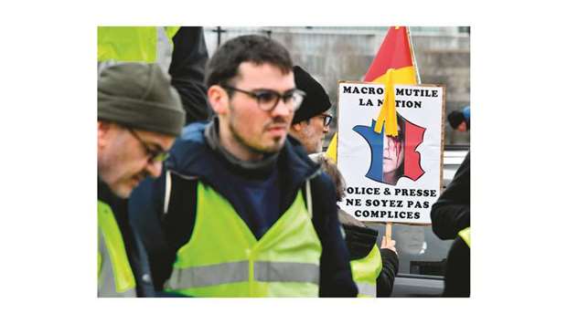 A March 9, 2019, file photo of a protester holding a placard reading u2018Macron mutilates the nationu2019 during an anti-government demonstration in Bordeaux.