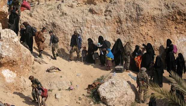 Islamic state fighters and their families walk as they surrendered in the village of Baghouz, Deir Al Zor province, Syria, yesterday.