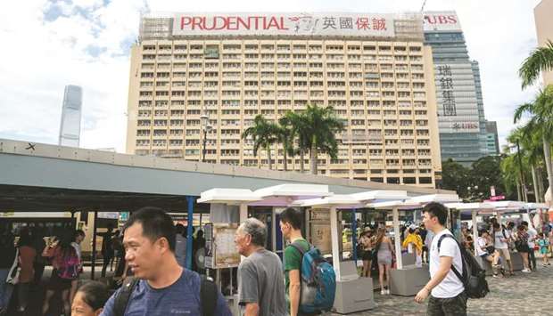 Pedestrians walk past as a banner featuring the Prudential logo is displayed atop a building in Hong Kong. John Foley, head of Prudentialu2019s UK business M&G Prudential, said the insurer had spent u00a327mn on setting up the new Luxembourg operation, which currently has 35 staff.