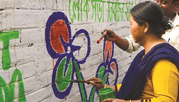Supporters of the All India Trinamool Congress (TMC) party paint on a wall their party symbol for the upcoming general election in Siliguri in West Bengal.
