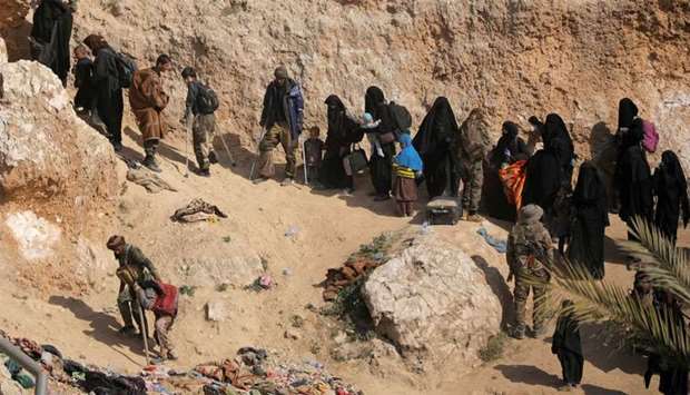 Islamic state fighters and their families walk as they surrendered in the village of Baghouz, Deir Al Zor province