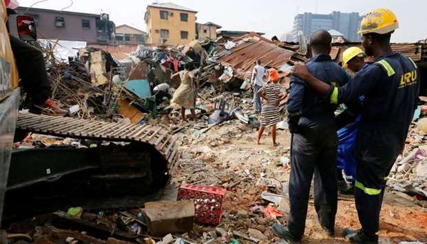 Rescuers are seen as people search for belongings at the site of a collapsed building in Nigeria's commercial capital of Lagos