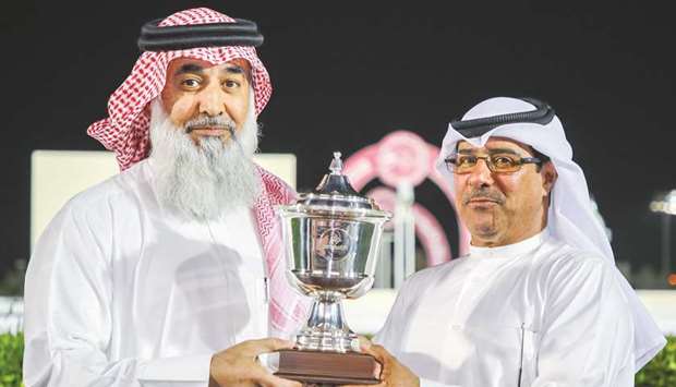 Qatar Racing and Equestrian Club (QREC) Racing manager Abdulla Rashid al-Kubaisi (right) presents the owneru2019s trophy after Itorio won the Ain Khaled Cup yesterday. PICTURES: Juhaim