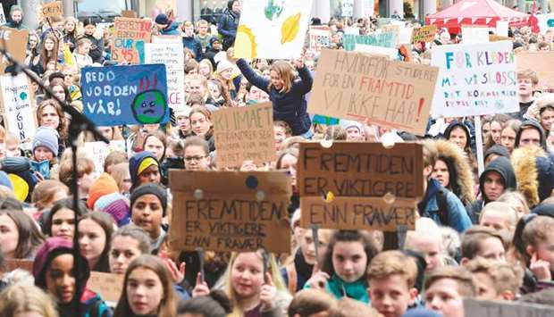 Schoolchildren hold placards during a climate protest yesterday at Torgalmenningen in Bergen, Norway.