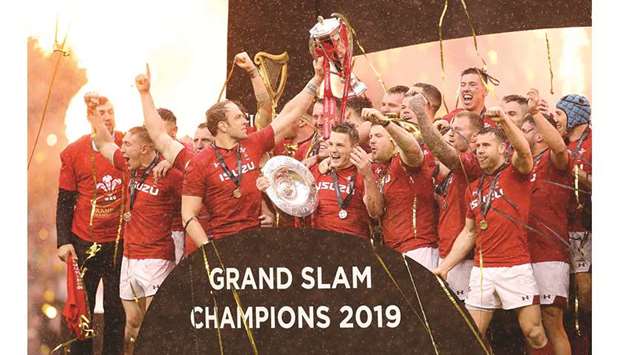 Wales players celebrate completing the Grand Slam, and winning the Triple Crown and Six Nations Championship with the trophies, after beating Ireland at the Principality Stadium in Cardiff yesterday. (Reuters)