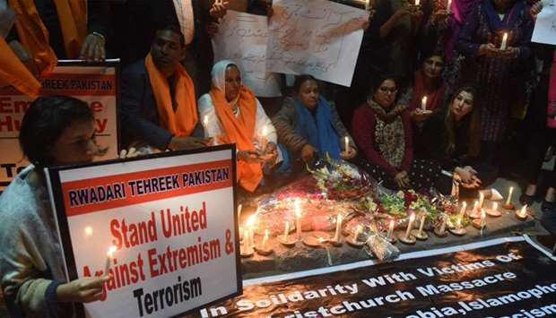 Pakistani demonstrators hold placard and candles during a candlelit vigil the day after the deadly attack on two mosques in Christchurch