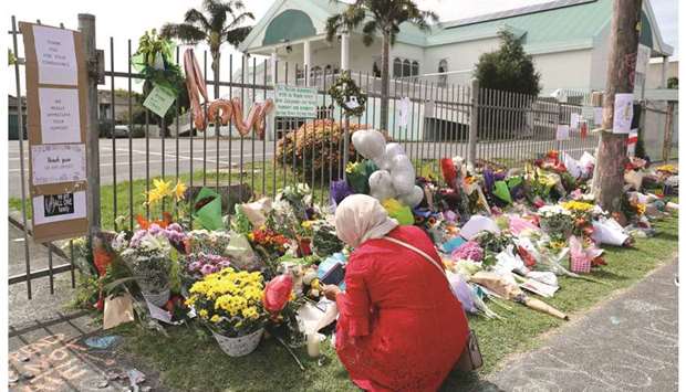 A resident pays respects by placing flowers for the victims of the mosque attacks in Christchurch at the Masjid Umar mosque in Auckland yesterday. (AFP)