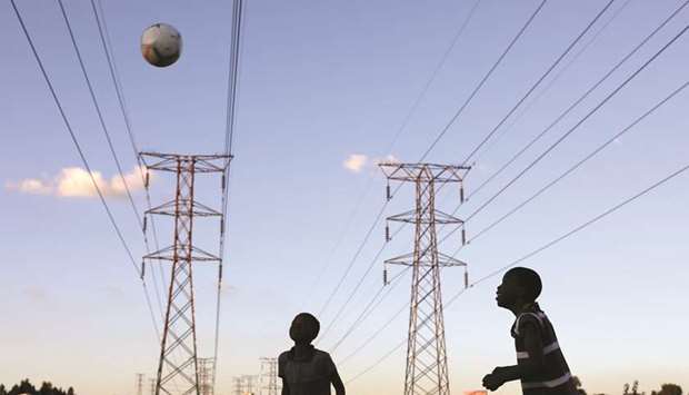 Boys play soccer below electricity pylons in Soweto, South Africa. Eskom is seen as one of the biggest risks to the countryu2019s economy, burdened by operational and financial woes stemming from years of mismanagement and massive cost overruns on two new coal-fired power stations that should have been completed in 2015.