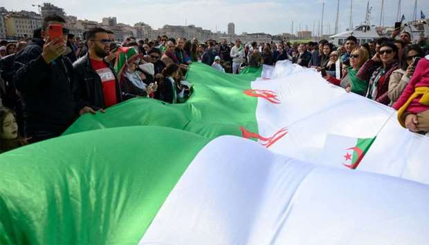 Demonstrators wave an Algerian flag during a protest over fears of plot to prolong the Algerian president's rule