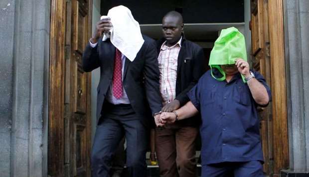 A Kenyan police officer escorts suspects, after fake currency was seized in a personal safety deposit box at the Queensway branch of Barclays Bank Kenya