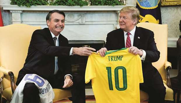 Brazilu2019s President Jair Bolsonaro presents a Brazil national soccer team jersey to US President Donald Trump after Trump gave him a US soccer team jersey during a meeting in the Oval Office of the White House in Washington, US, yesterday.