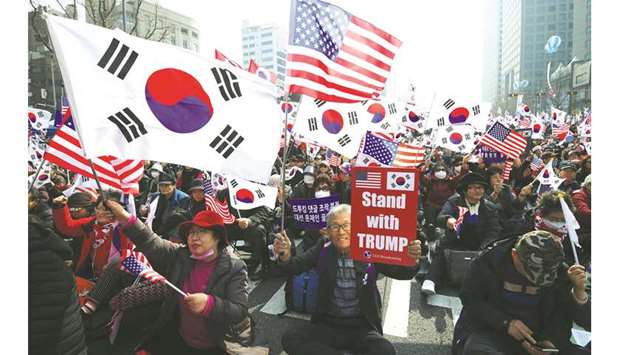 Pro-US protesters wave South Korea and US flags during a rally denouncing the South Korean governmentu2019s dovish policies on North Korea, in Seoul.
