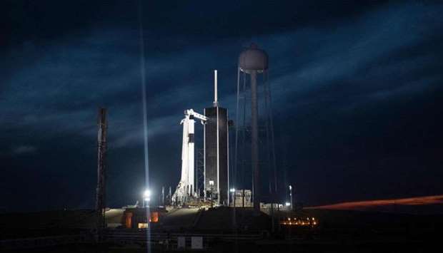SpaceX Falcon 9 rocket with the company's Crew Dragon spacecraft onboard illuminated on the launch pad by spotlights at Launch Complex 39A as preparations continue for the Demo-1 mission