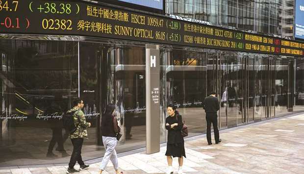 Pedestrians walk past an electronic ticker board displaying stock prices outside the Hong Kong Stock Exchange. The index dropped 0.5% to 29,320.97 points yesterday after a four-day rally.