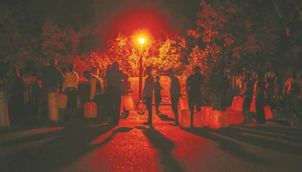 Residents illuminated by a streetlight queue to fill water bottles and containers at night at the Newlands natural water spring in Cape Town, South Africa, on February 7, 2018. A study published by the African Development Bank last year found the continent needs to spend at least $130bn to address an infrastructure backlog, including as much as $66bn on providing universal access to water and sanitation, but faces a financing gap of $68bn to $108bn.