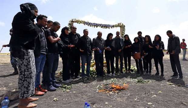 Relatives pay homage to victims near burning candles during a commemoration ceremony at the scene of the Ethiopian Airlines Flight ET 302 plane crash, near the town Bishoftu