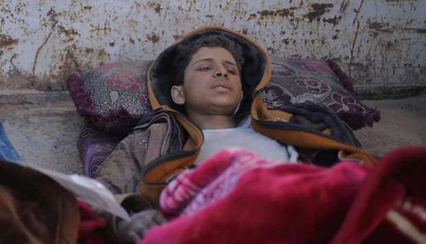 Hareth Najem, an Iraqi orphan lies under a blanket in a truck, near the village of Baghouz, Deir Al Zor province, Syria