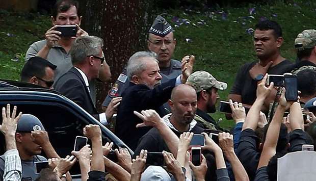 Brazilian former president  Luiz Inacio Lula da Silva (C-waving) is escorted by security forces upon arrival at Jardim da Colina cemetery, in Sao Bernardo do Campo, Sao Paulo, Brazil after leaving the Federal Police headquarters in Curitiba, Parana state, where he is serving a 12-year prison sentence, to attend the funeral of his grandson