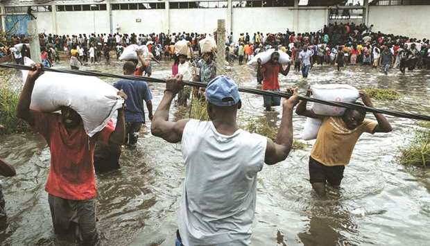 People loot sacks of rice from a warehouse which is surrounded by water after cyclone hit in Beira, Mozambique. Six days after Idai cut a swathe through Mozambique, Zimbabwe and Malawi, the confirmed death toll stood at more than 300 and hundreds of thousands of lives were at risk, officials said.