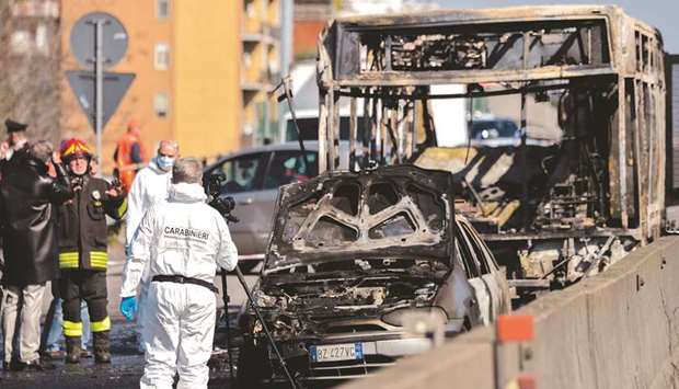 Forensic policemen and firefighters work by the wreckage of a school bus after it was torched by the driver in San Donato Milanese, southeast of Milan.
