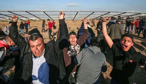 Palestinians chant slogans as they march carrying a steel-wire mesh during a protest at the border fence with Israel east of Gaza City, yesterday.