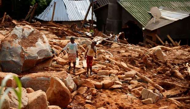 Children carry drinking water yesterday over debris created by Cyclone Idai at Peacock Growth Point in Chimanimani, on the border with Mozambique, Zimbabwe