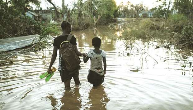 Rosita Moises Zacarias (left) holds the hand of her sister Joaninha Manuel, as they walk in flooded waters from their home destroyed by the cyclone Idai, to go to sleep in a shelter in Buzi, Mozambique.