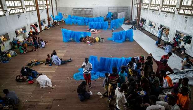 People gather to receive food given to the displaced people in a hall where they are living at the Samora Machel High School in Beira, Mozambique