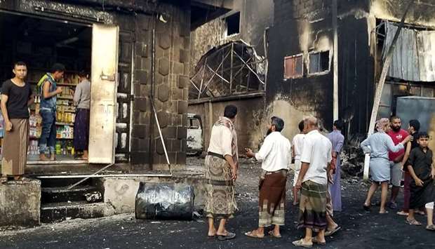 Yemeni men speak yesterday in the street by destroyed and burnt buildings in the country's third city of Taez.