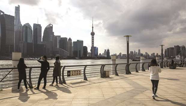 People walk through the North Bund area as skyscrapers of the Pudong Lujiazui Financial District stand across the Huangpu River in Shanghai (file). A softening economy, muted inflation and measures to contain property bubbles have weighed on revenue growth as well as alternative funding sources such as land sales, prompting Nobel laureate Joseph Stiglitz to urge the government to consider increasing some taxes as it restructures the economy.