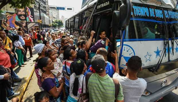 People queue to get on a bus during a partial power cut in Caracas as the subway stations were closed and the underground trains stalled on their tracks.