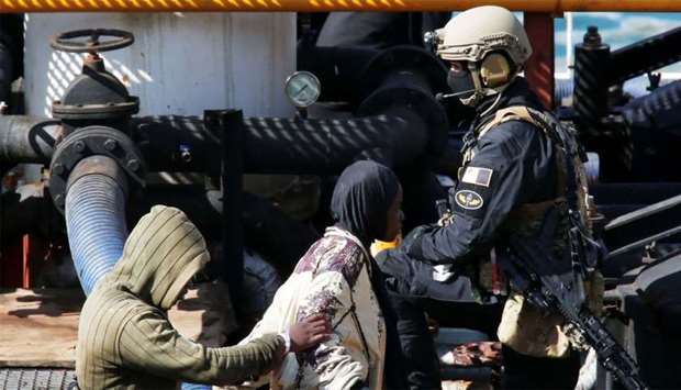 A Maltese special forces soldier guards a group of migrants on the merchant ship Elhiblu 1 after it arrived in Senglea