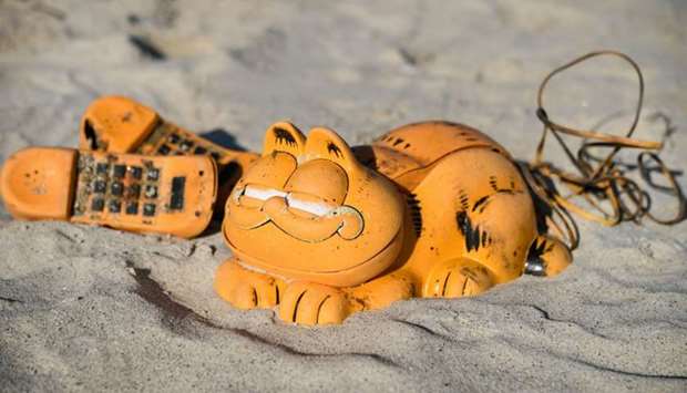 Spare parts of plastic 'Garfield' phones are displayed on the beach on March 28, 2019 in Plouarzel, western France, after being collected from a sea cave by environmental activists