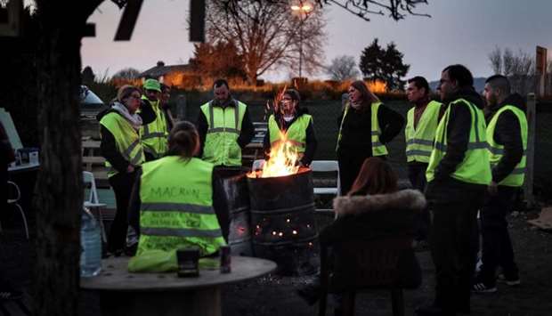 Yellow vest (Gilets jaunes) protestors gather around a fire as they occupy a makeshift camp constructed near a traffic circle, on March 28, 2019 in Noyon