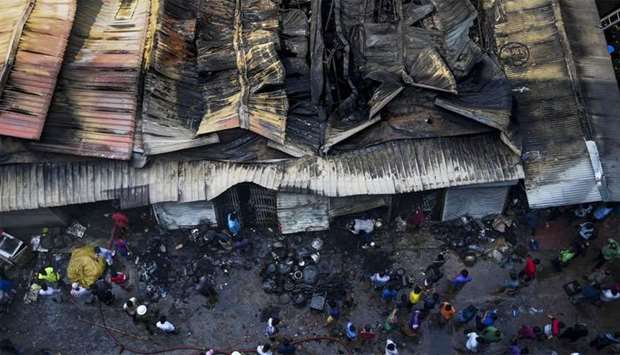 Bangladeshi shop owners gather as they look at their burnt belongings after a fire break out in a makeshift market in Dhaka